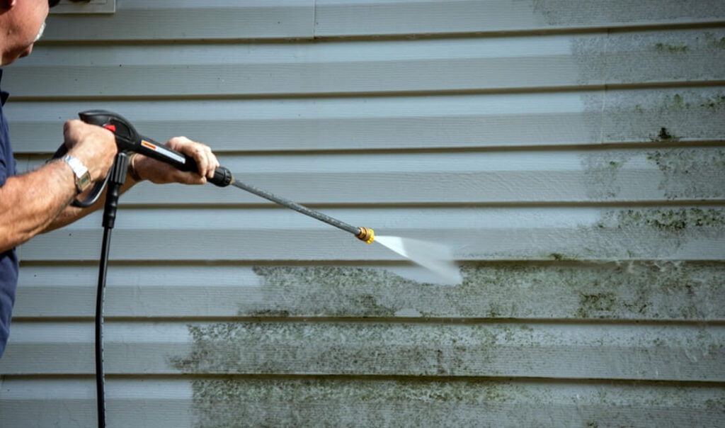 man power washing home siding