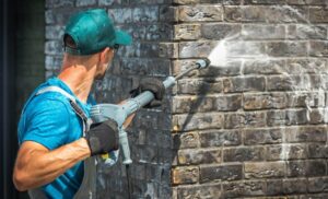 cleaning person pressure washing brick wall