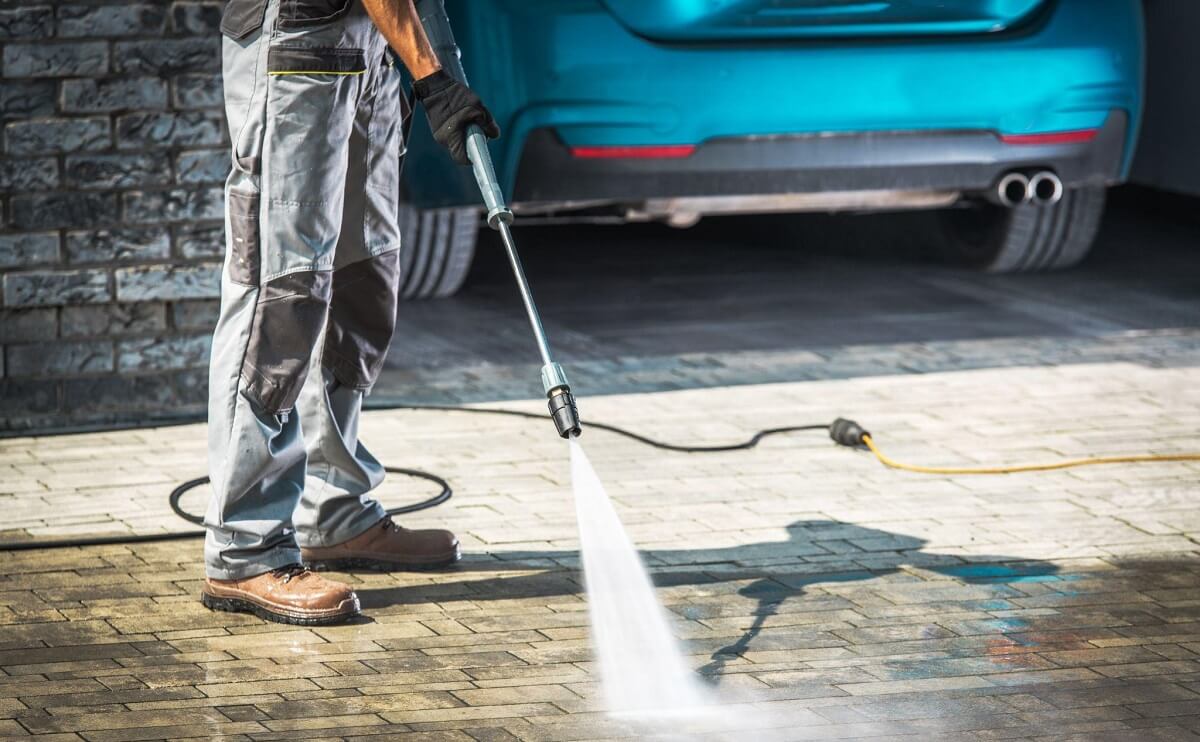 man pressure washing driveway