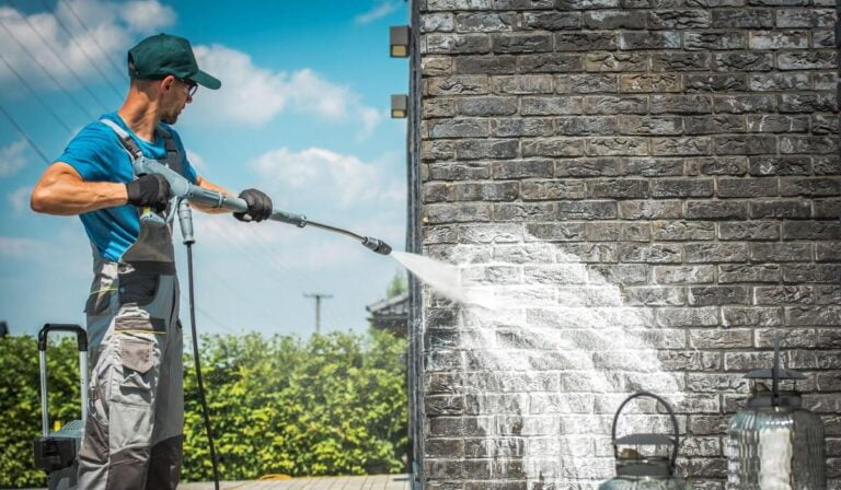 man pressure washing home