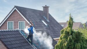 man pressure washing home roof