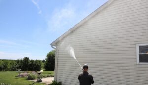 man pressure washing house