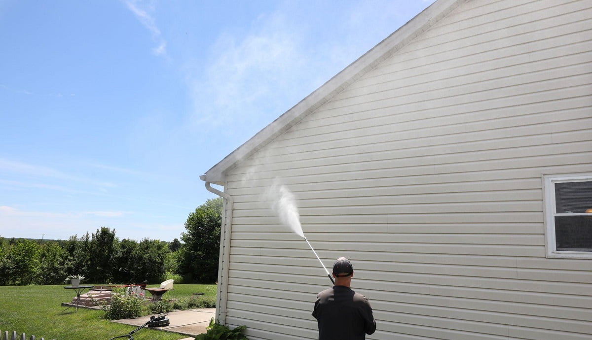 man pressure washing house